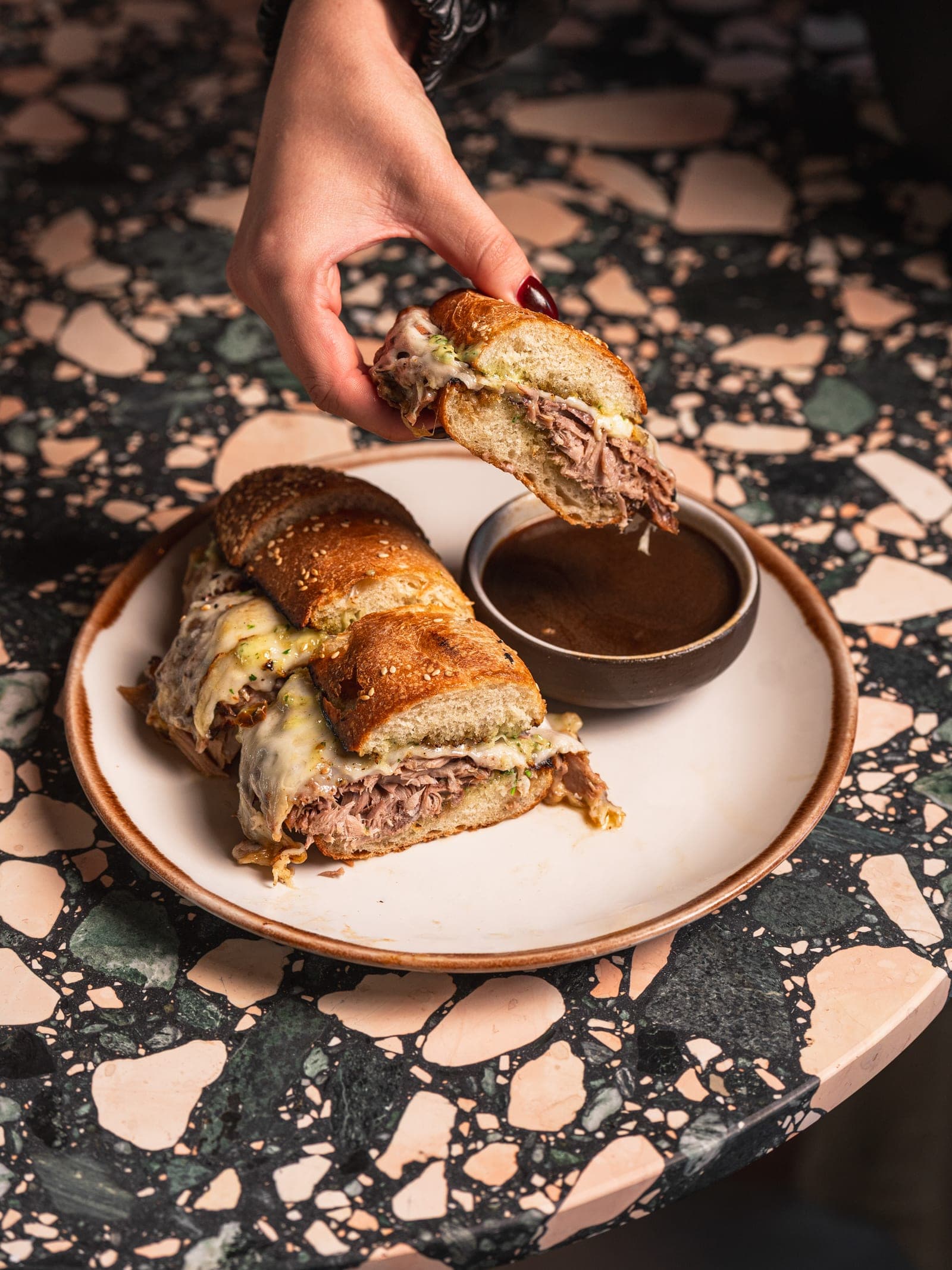 A roast pork sandwich with a cup of jus